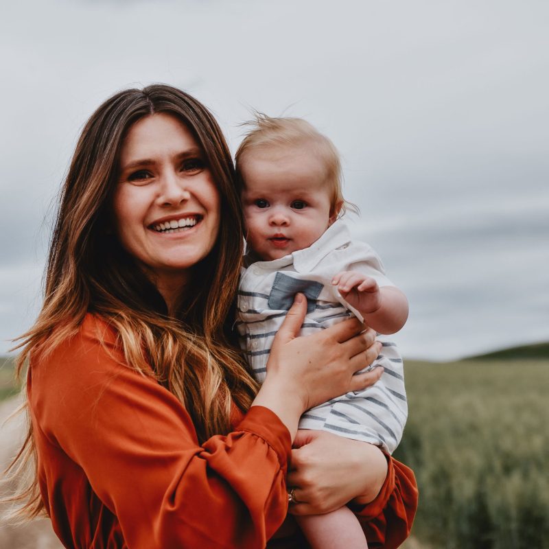 A new mother going through the postpartum period is holding her son and smiling